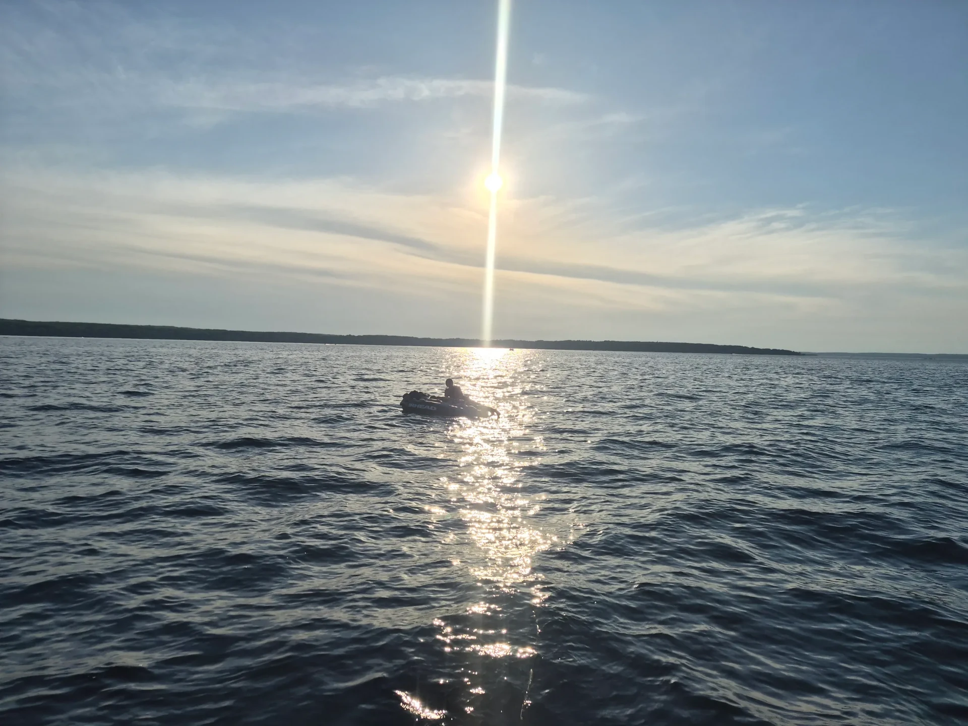 A small boat on the bay under a bright evening sun