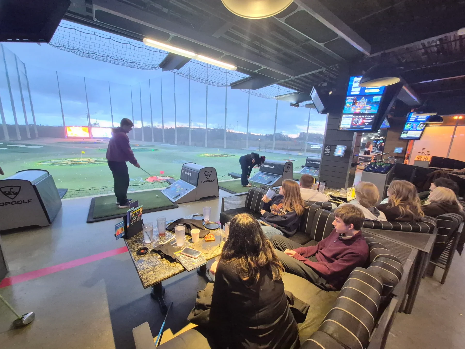 Families gathered at a Topgolf bay in the evening