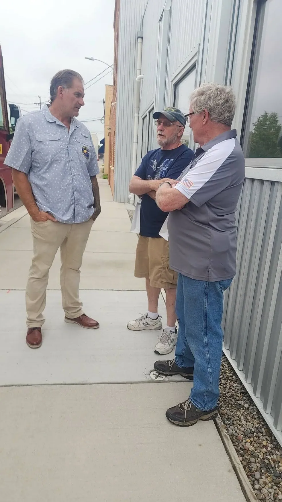 Three people talking together outside a community building