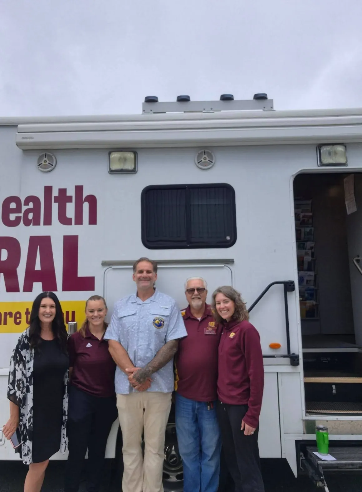 Camp Valor and CMU Health team members standing together in front of the mobile health vehicle